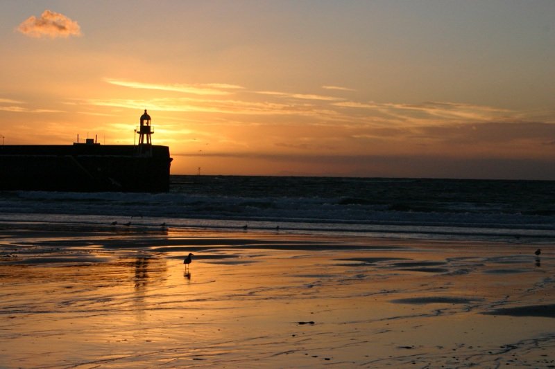 Sun setting behind lighthouse
